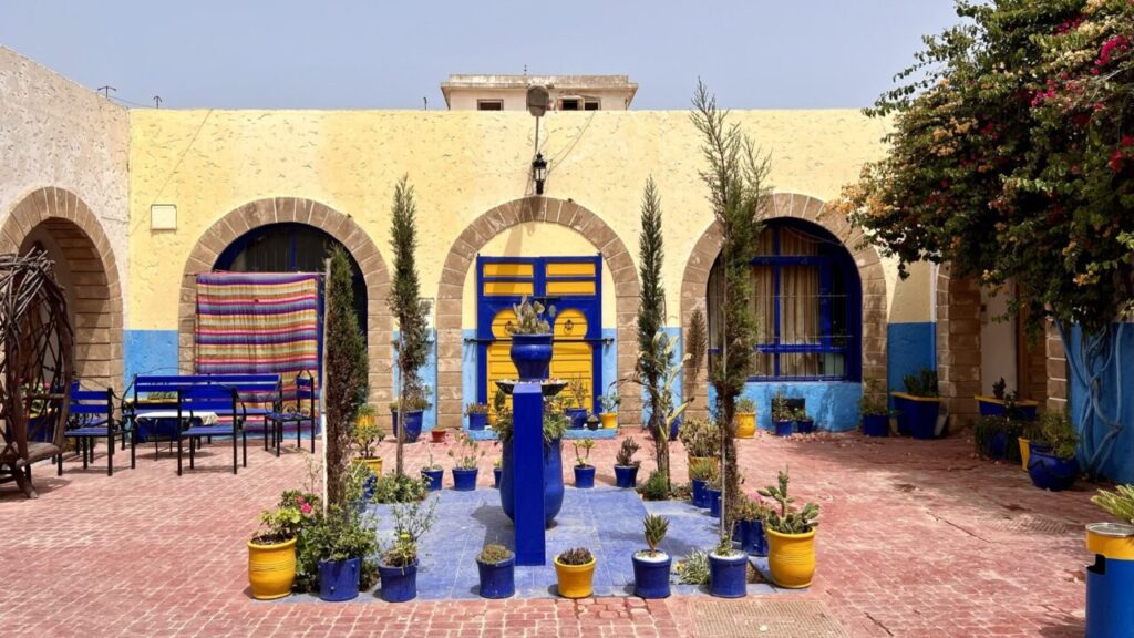 Blue courtyard with yellow pots and archways in Essaouira